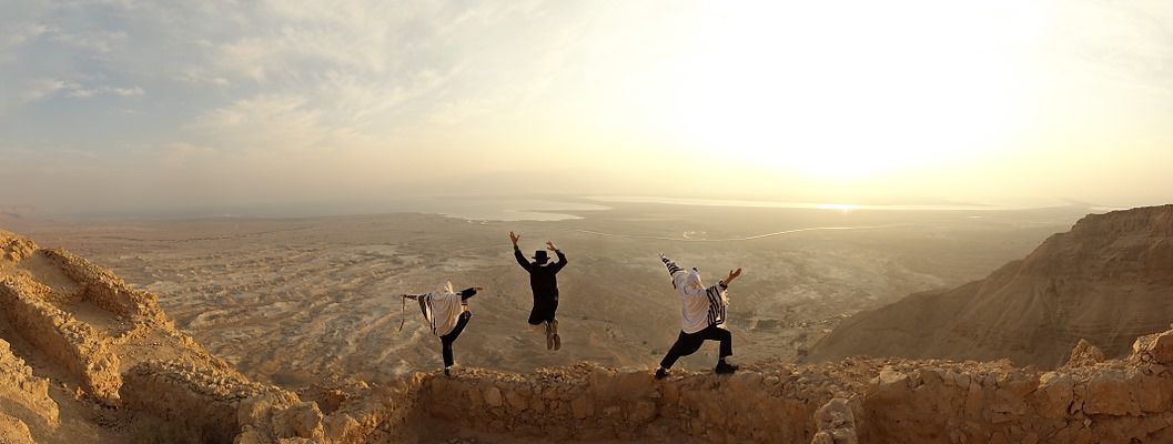 Photo of 3 people on a cliff at sunrise