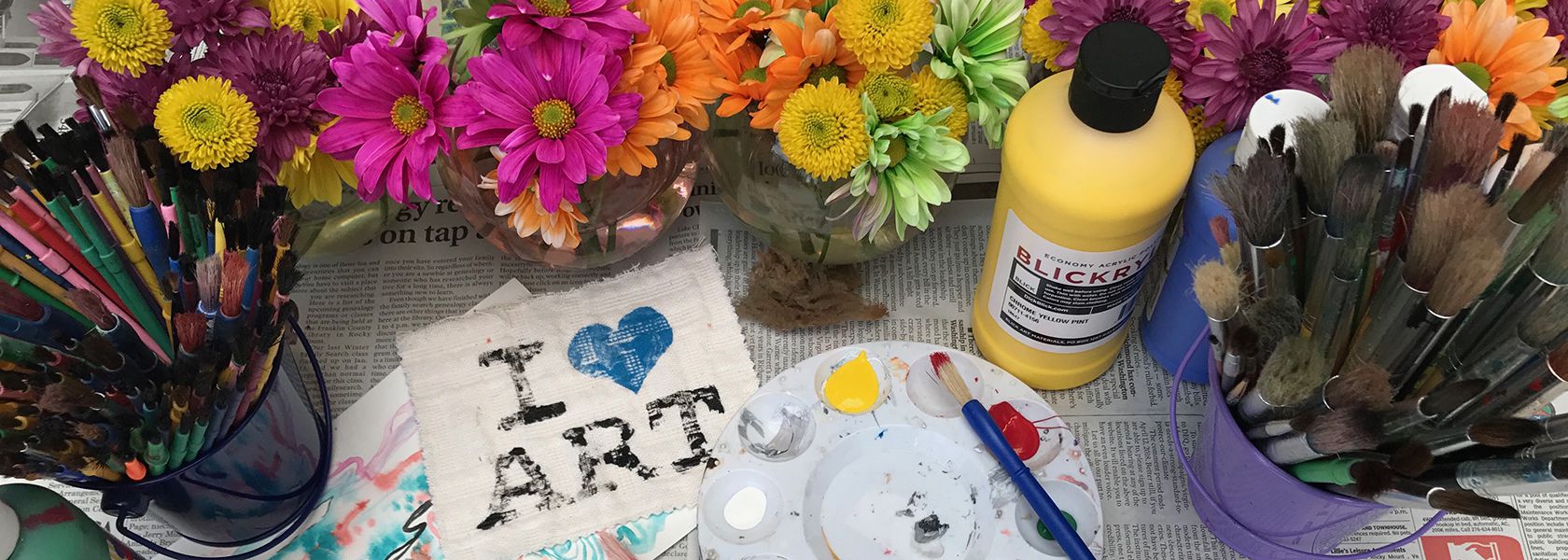 colorful art supplies and flowers on a table with a paper that says 