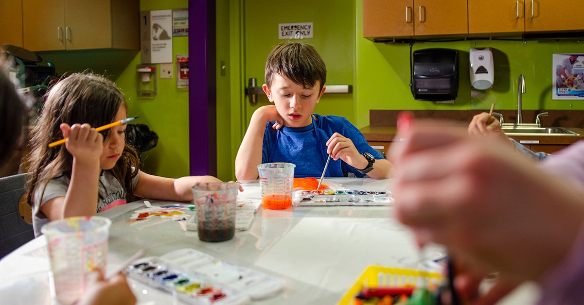 young boy painting at table