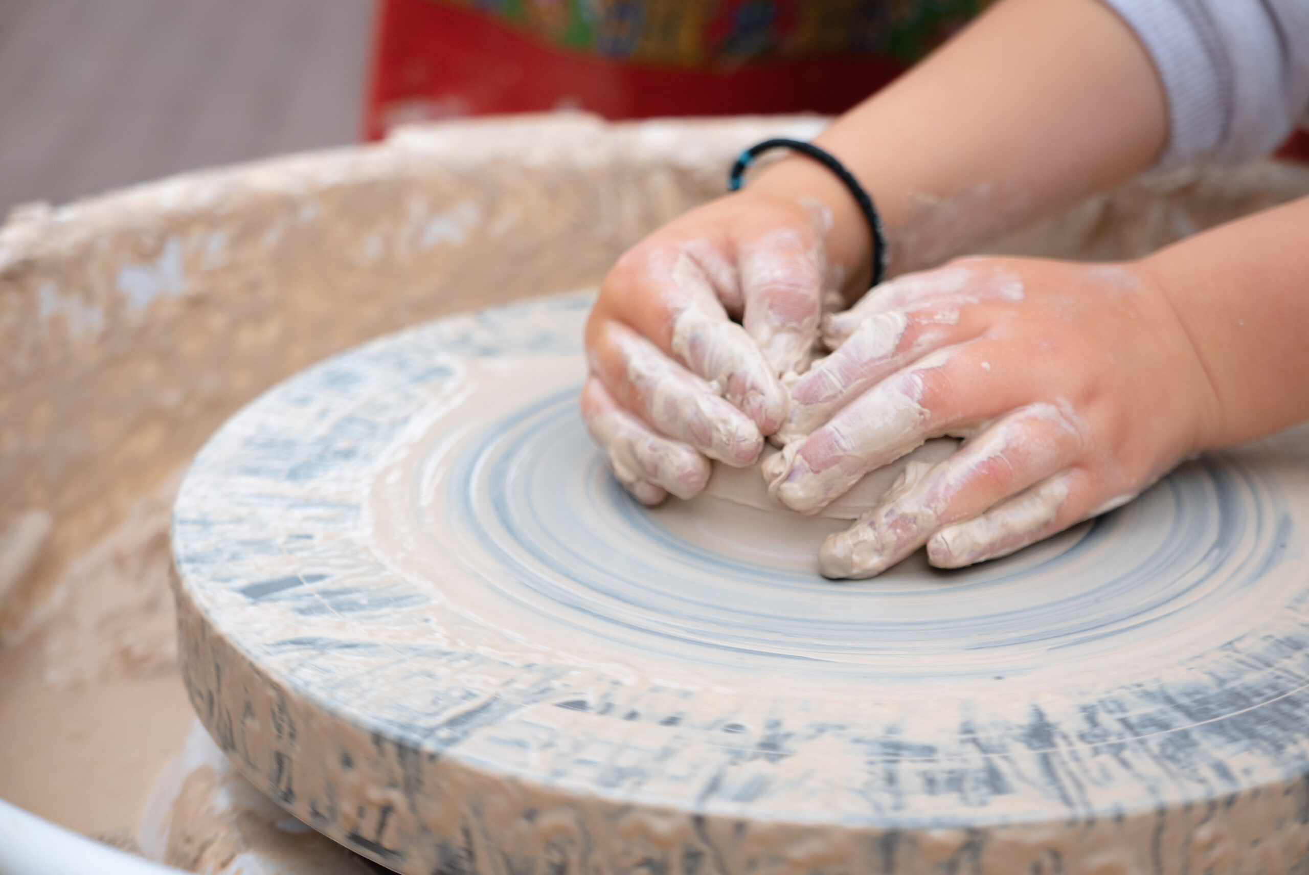 Child shaping clay on a wheel