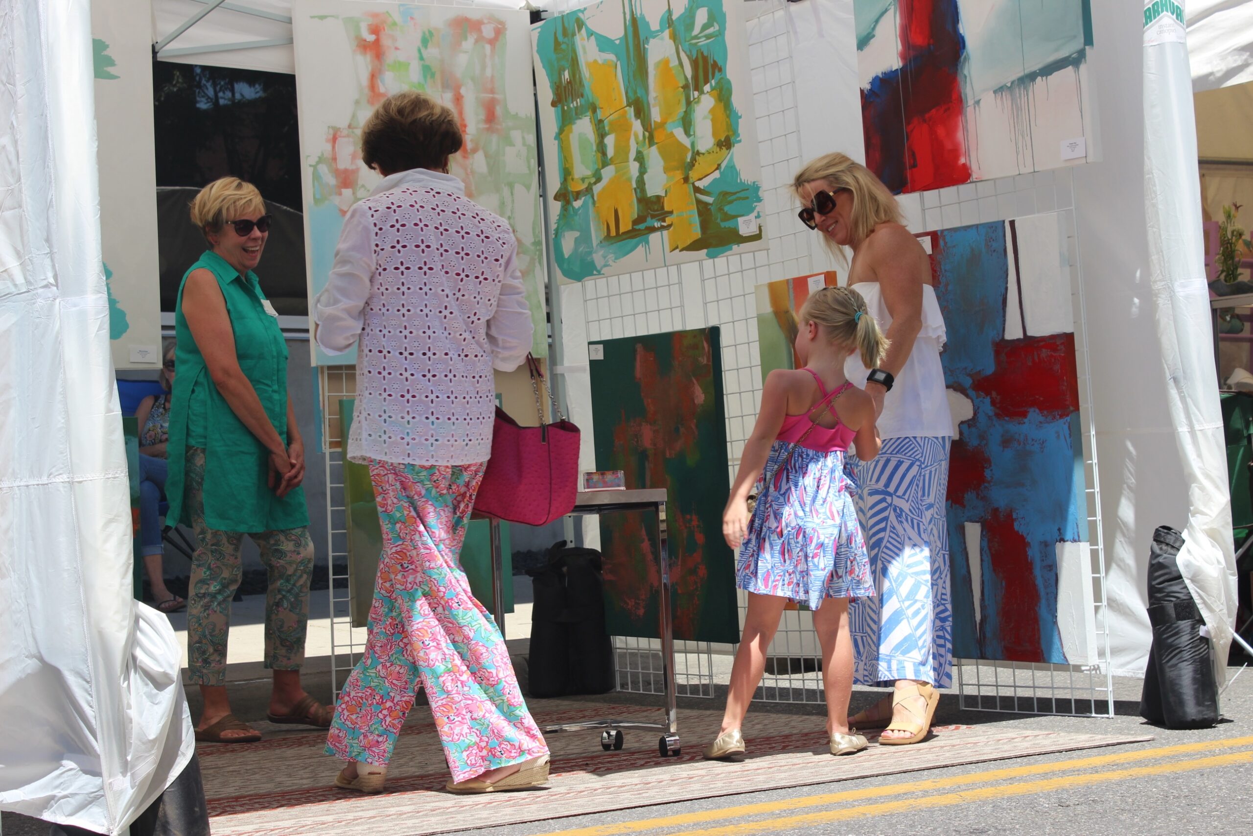 Four people looking at art in an outdoor artist's tent