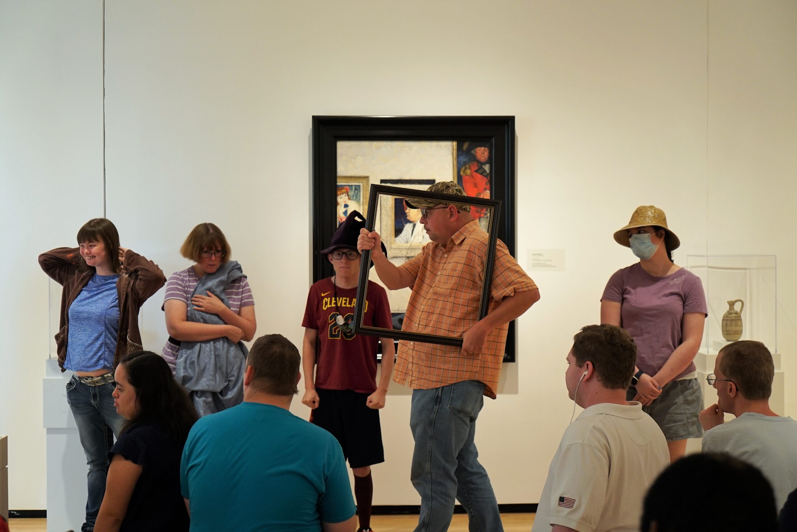 A man carrying a picture frame through a room of art