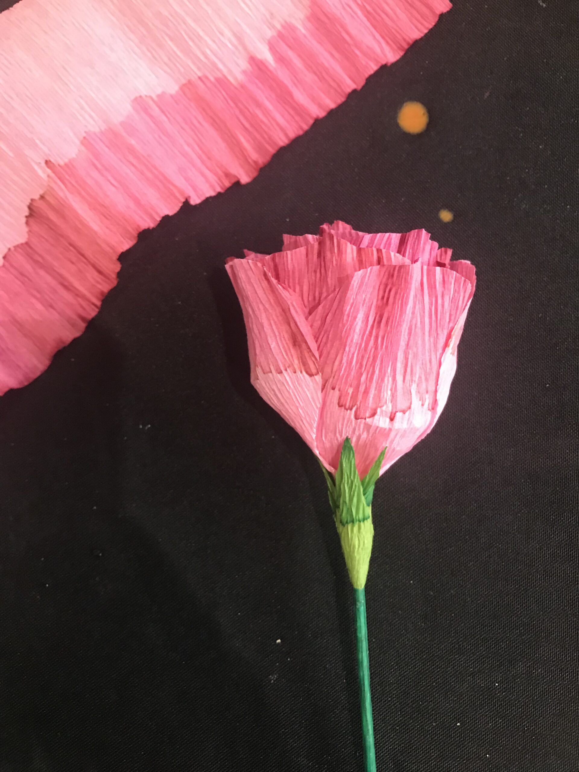 A pink paper rose with a green stem