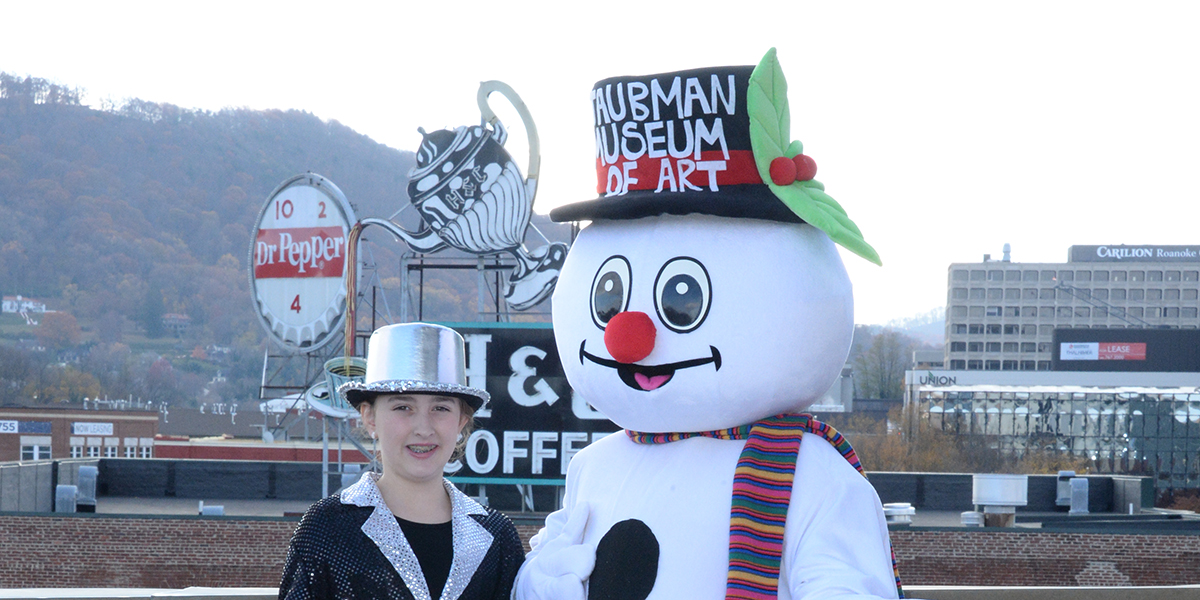 A child in a silver hat standing next to a Frosty the Snowman plush costumed figure