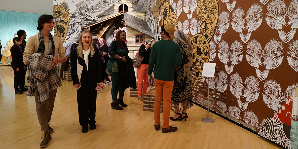 A group of people walking through an art gallery talking and smiling