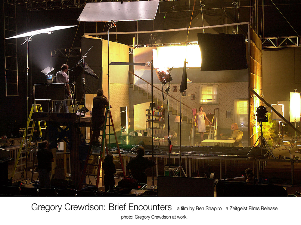 A film crew filming a scene of a brightly lit room with a woman standing in it