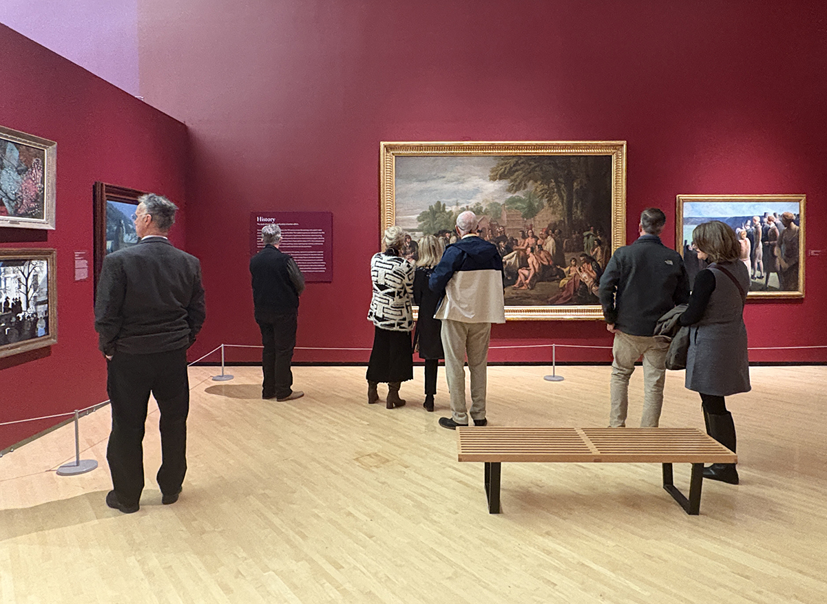 A group of people standing in a gallery looking at paintings
