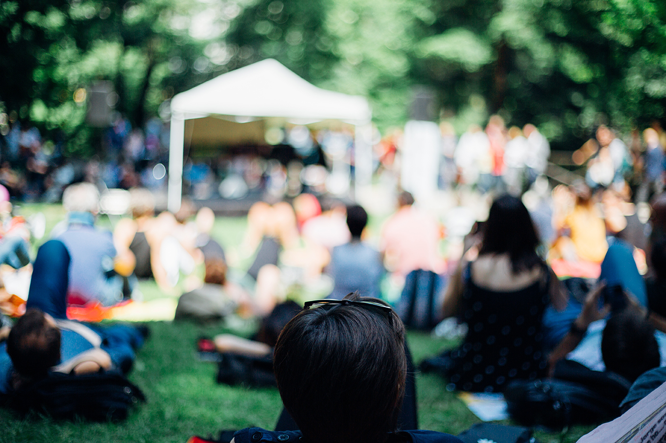 People sitting and lying in the grass listening to music in an outdoor setting