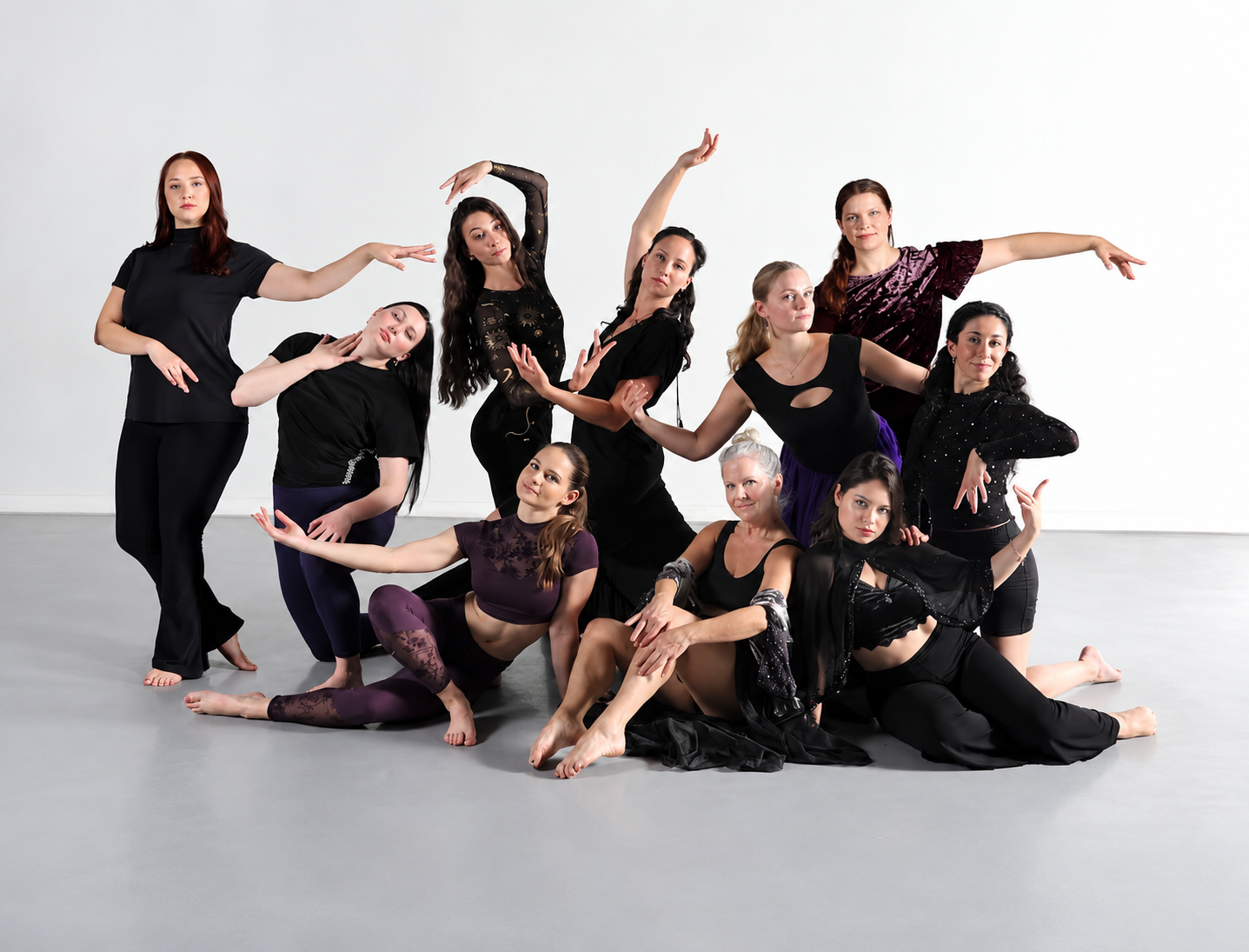 A group of women dressed in black pose in various dance moves
