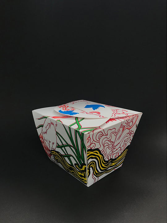 a takeout box painted in bright swirls sitting on a dark black and gray background